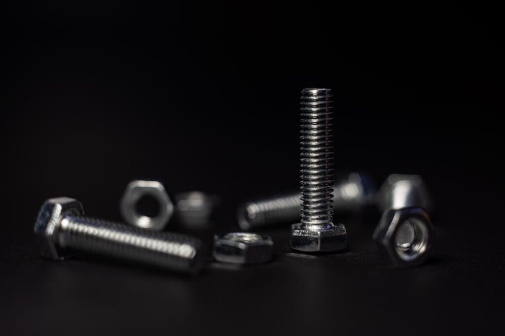 Bolt Detailed close-up of metal screws and nuts with a dark background highlighting textures and shapes.